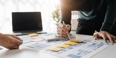 Ux developer and ui designer brainstorming about mobile app interface wireframe design on table with customer breif and color code at modern office.Creative digital development agency photo