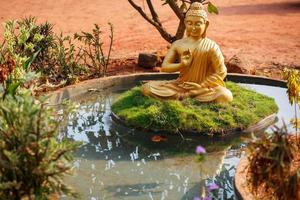 Golden buddha statue by the pond in Goa photo