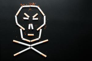 Skull from cigarettes on a black background. The concept of smoking kills. Toward the concept of smoking as a deadly habit, nicotine poisons, cancer from smoking, illness, quit smoking. photo