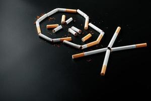 Skull from cigarettes on a black background. The concept of smoking kills. Toward the concept of smoking as a deadly habit, nicotine poisons, cancer from smoking, illness, quit smoking. photo