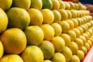 A stack of yellow ripe and sweet lines on the whole screen on the market. Lime and lemons background. Fresh organic lemons and lime on a local farmer photo