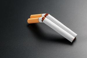 dos cigarrillos en forma de escopeta de dos cañones sobre un fondo negro con espacio para copiar. deja de fumar. el concepto de fumar mata.