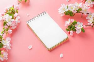 Blooming spring sakura on a pink background with notepad space for greeting message. The concept of spring and mother's day. Beautiful delicate pink cherry flowers in springtime photo
