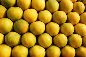 A stack of yellow ripe and sweet lines on the whole screen on the market. Lime and lemons background. Fresh organic lemons and lime on a local farmer photo