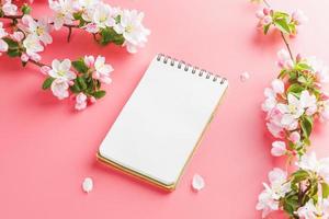 Blooming spring sakura on a pink background with notepad space for greeting message. The concept of spring and mother's day. Beautiful delicate pink cherry flowers in springtime photo