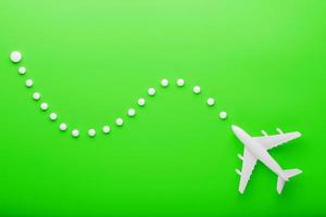 avión de pasajeros blanco con puntos de trayectoria como en un mapa de ruta, aislado con un fondo verde brillante. foto