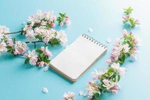 Blooming spring sakura on a blue background with notepad space for a greeting message. The concept of spring and mother's day. Beautiful delicate pink cherry flowers in springtime photo