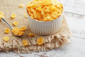 Bowl with golden flakes on a linen, on a light wooden table, next to a spoon. Rustic country style. View from above photo