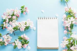 Blooming spring sakura on a blue background with notepad space for a greeting message. The concept of spring and mother's day. Beautiful delicate pink cherry flowers in springtime photo