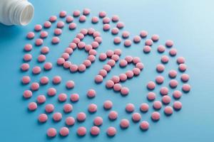 Pink tablets in the form of vitamins B12 in the heart on a blue background, spilled from a white can low contrast photo