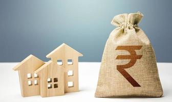 Indian rupee money bag and residential buildings. Mortgage loan. Costs of service and maintaining buildings. Property tax. Investment in real estate. Purchase of housing. City municipal budget.