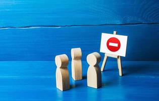 People look at the easel with no stop entry symbol. Prohibition of actions and operations, restricted area. Wrong direction. Ban and sanctions. Isolation zone and quarantine. Inaccessibility, taboo. photo