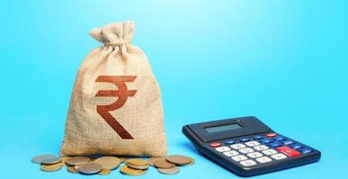 Indian rupee money bag and calculator. Accounting concept. Analysis of loan selection. Income and expenses. Calculation of damage and insurance payments. Summing up the financial results. Budgeting. photo