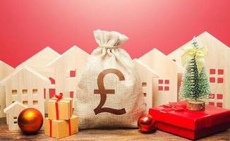 British pound sterling money bag and houses in a New Year's setting. New Year or Xmas winter holiday. Increase in investment attractiveness. Promotions, offers. Mortgage loans. Bank deposit photo