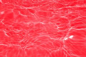 Defocus blurred transparent red colored clear calm water surface texture with splashes and bubbles. Trendy abstract nature background. Water waves in sunlight with copy space. Red watercolor shining photo