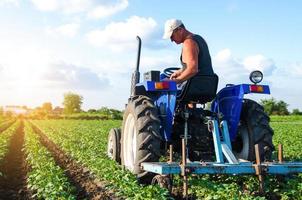 un agricultor en un tractor trabaja en el campo. un trabajador agrícola labra la tierra en una plantación. maquinaria agrícola. cuidado de cultivos. arar y aflojar la tierra. agroindustria y agroindustria. paisaje agrícola foto