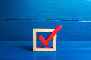 Red voting check mark on a blue background. Voting concept for democratic elections. Make the best choice, solve the problem. Social poll. Rights and freedoms. Lawmaking. Approval symbol photo