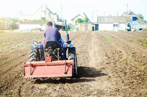 The farmer drives a tractor with a milling unit equipment. Loosening surface, land cultivation Use of agricultural machinery and to simplify and speed up work. Farming, agriculture. Plowing the field. photo