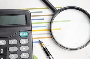 magnifying glass and working paper with calculator with pen photo