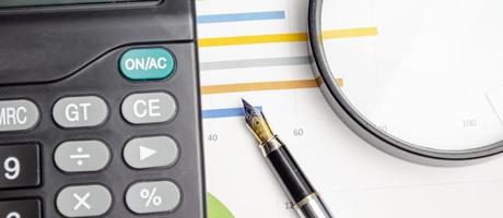 Business concept with magnifying glass, calculator, pen, pencils and financial documents photo