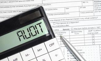 audit word on calculator display with pen and tax forms photo