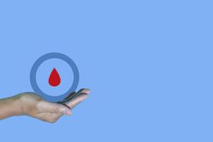 Top view inscription world diabetes day and hand gesture with red blood drop in man hands isolated on a blue background. World diabetes day, 14 november. Copy space, Health Awareness photo
