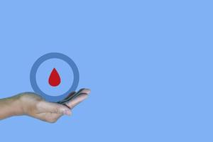 vista superior inscripción día mundial de la diabetes y gesto de mano con gota de sangre roja en manos de hombre aisladas en un fondo azul. Día mundial de la diabetes, 14 de noviembre. copie el espacio, la conciencia de la salud foto