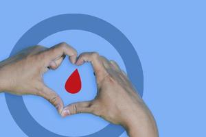 Top view inscription world diabetes day and hand gesture with red blood drop in man hands isolated on a blue background. World diabetes day, 14 november. Copy space, Health Awareness photo