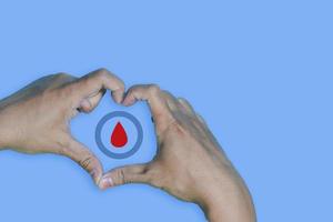 Top view inscription world diabetes day and hand gesture with red blood drop in man hands isolated on a blue background. World diabetes day, 14 november. Copy space, Health Awareness photo