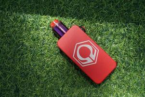 Sangatta, East Kalimantan, Indonesia, 2020 - Red Hexohm vape mod V3 with america berakfast liquid on green grass. Hexohm is premium mod vape. photo