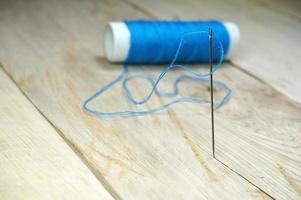 Blue threads and sewing needles on the wooden table. Selective focus to sewing needle photo