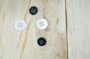 Black and white shirt buttons on wooden table photo
