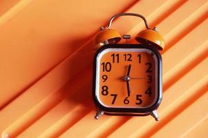 Orange alarm clock on orange plactic background photo