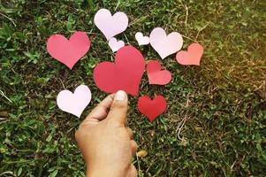 Hand holding heart shape paper on green grass photo