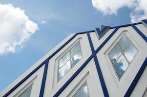 Sangatta, East Kutai, East Kalimantan, Indonesia, 2022 - Blue and white modern architecture with Pentagon glass windows. Blue sky and cloud reflection. photo