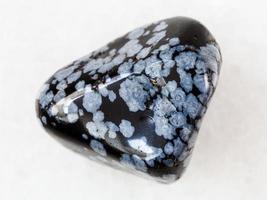 pebble of snowflake obsidian gem stone on white photo