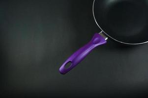 Purple frying pan isolated on black or dark backround. Selective focus. photo
