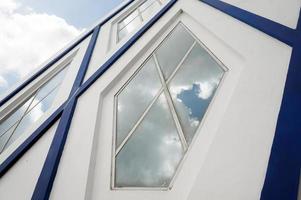 Sangatta, East Kutai, East Kalimantan, Indonesia, 2022 - Blue and white modern architecture with Pentagon glass windows. Blue sky and cloud reflection. photo