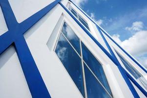 Sangatta, East Kutai, East Kalimantan, Indonesia, 2022 - Blue and white modern architecture with Pentagon glass windows. Blue sky and cloud reflection. photo