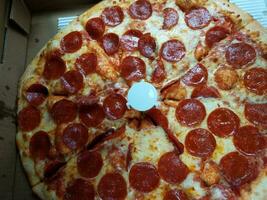 pepperoni pizza with cheese and a white plastic support photo