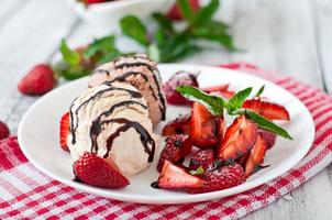 Ice cream with strawberries and chocolate on a white plate photo