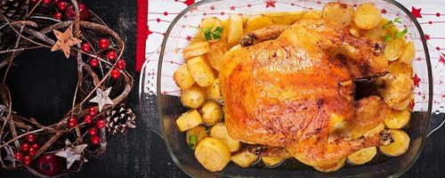 Baked turkey or chicken. The Christmas table is served with a turkey, decorated with bright tinsel. Fried chicken, table. Christmas dinner.  Top view, banner photo