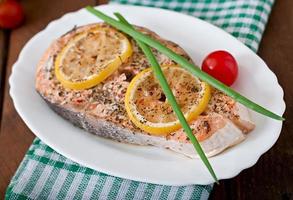 Baked salmon steak with herbs, lemon and salad photo