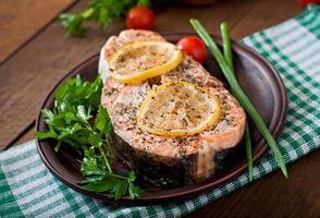 Baked salmon steak with herbs, lemon and salad photo