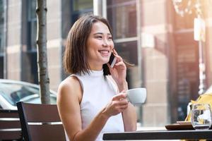 mujer asiática que trabaja en una computadora portátil en un café. mujer joven que trabaja en una computadora portátil. hermosa joven que trabaja con una laptop de una cafetería. mujer atractiva sentada en un café con una laptop foto