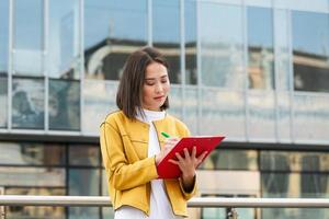 Asian Businesswoman in casual wear writing on clipboard. business woman holding clipboard. Modern, hardworking woman holding clip board in hands, writing on documents. photo