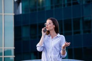 mujer de negocios que recibe malas noticias en un teléfono inteligente en la calle con edificios de oficinas en el fondo foto