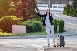 Smiling young woman tries to stop taxi, calling taxi photo