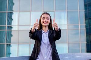 Confident young businesswoman giving the thumbs up. portrait of young business woman at modern startup company showing thumbs up photo