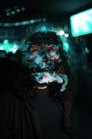 hombre en capucha con el pelo largo y desaliñado con una máscara brillante de neón. foto